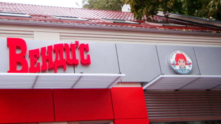 Wendy's restaurant facade with large red Cyrillic lettering, mascot logo, and red awnings.
