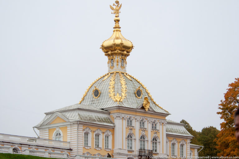 Yellow-and-white palace pavilion with faceted roof, gilded ornament, and double-headed eagle finial.
