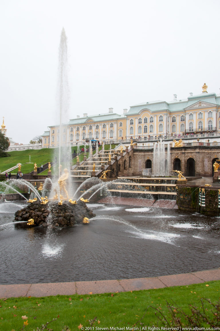 Wide Grand Cascade basin with radial fountains, gilded figures, terraces, and Grand Palace above.