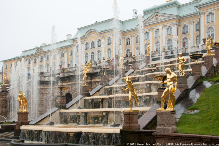 Grand Cascade steps with flowing water and gilded statues rising toward the yellow-and-white Grand Palace.