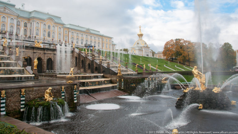 Grand Cascade with gilded statues and arcing fountains below the pale Grand Palace at Peterhof.