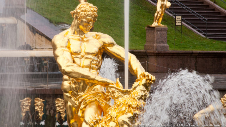 Gilded muscular male fountain figure surrounded by forceful water jets in the Grand Cascade.