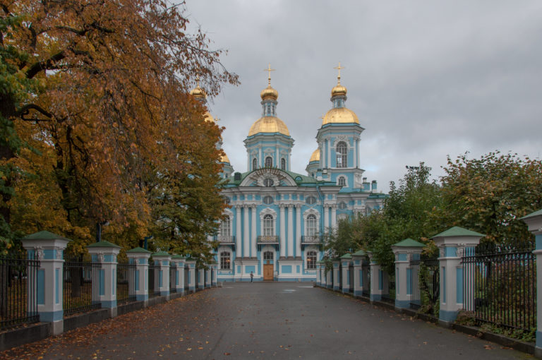 Tree-lined path and fenced approach leading directly to the turquoise-and-white St. Nicholas Naval Cathedral.
