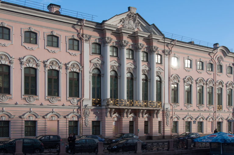 Sunlit pink-and-white Beloselsky-Belozersky Palace façade with giant columns, ornate windows, and central balcony.