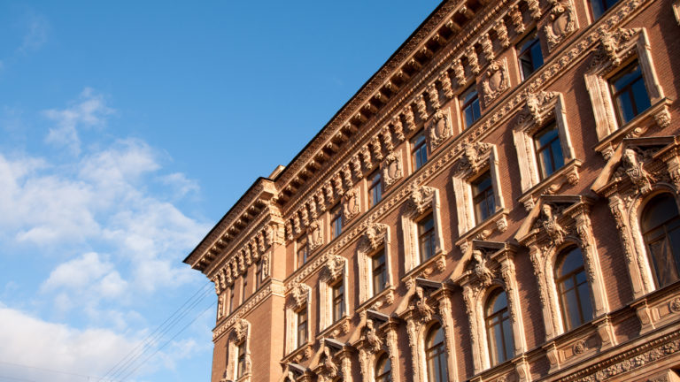 Low-angle view of the ornate pink Beloselsky-Belozersky Palace façade with pale sculptural window surrounds against blue sky.