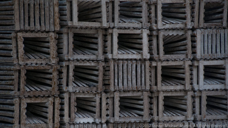 Close view of a weathered wooden lattice made of repeating square panels with diagonal and vertical slats.
