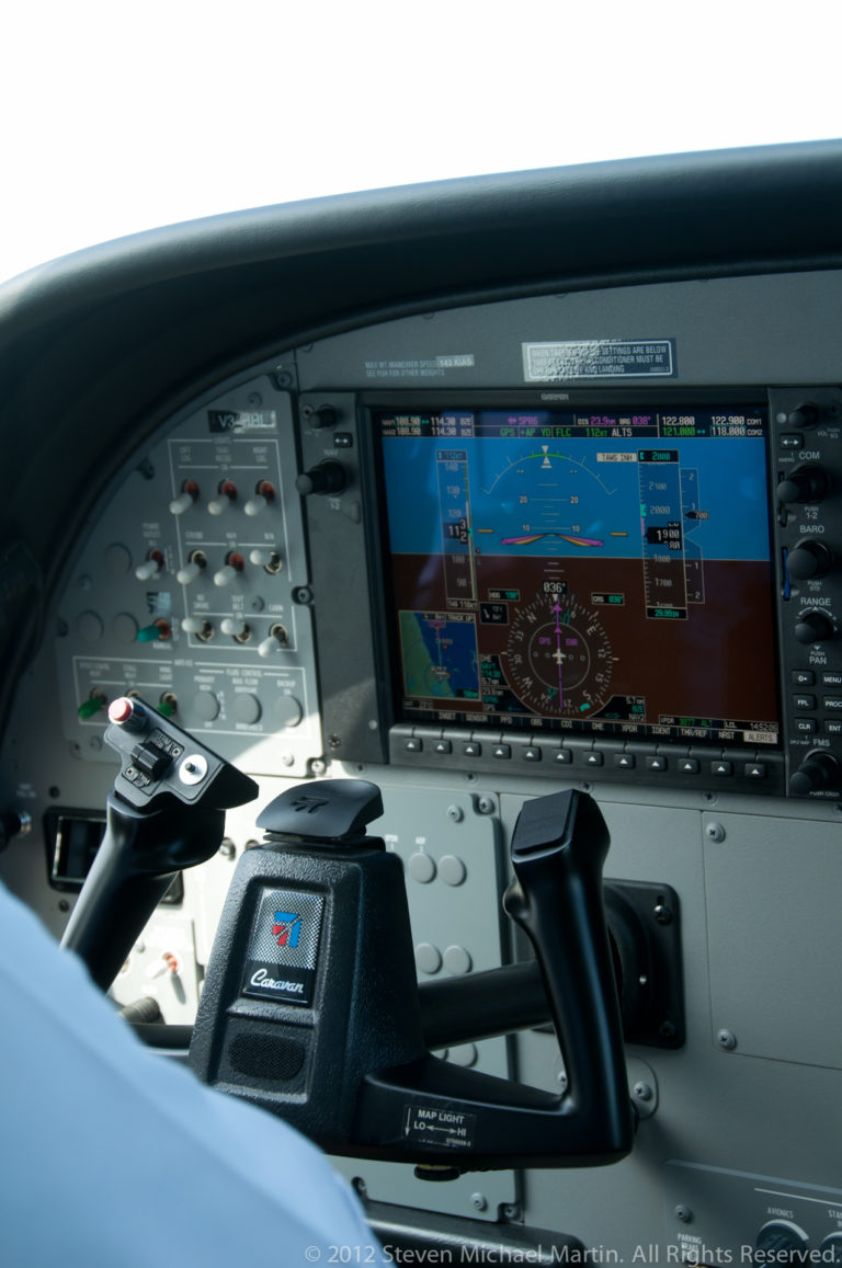 Small-aircraft cockpit with dual control yokes and illuminated electronic flight displays.