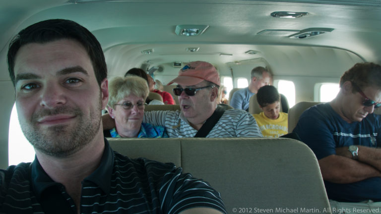 Several passengers seated closely together inside the narrow cabin of a small commuter aircraft.