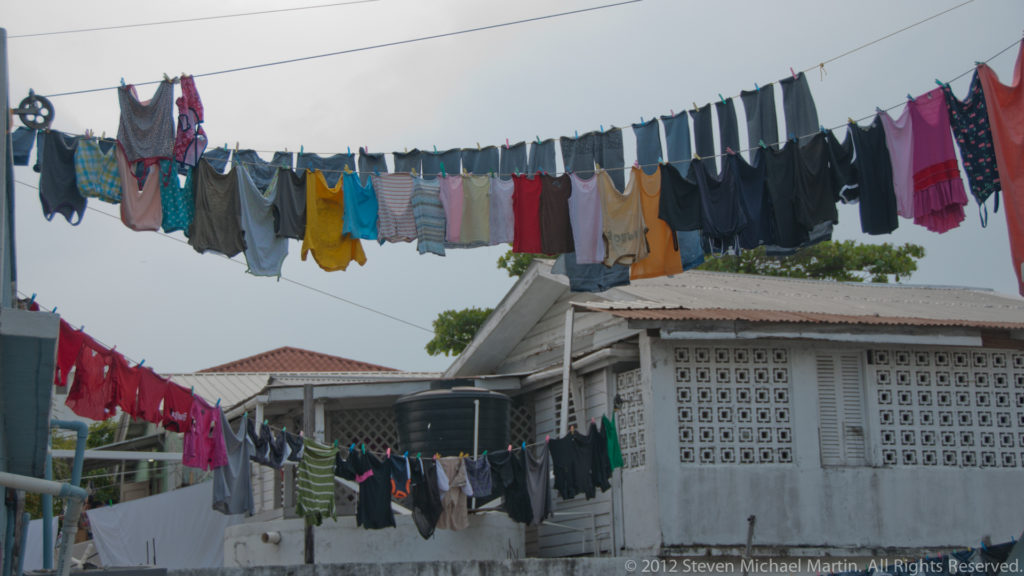 Rows of colorful laundry hanging on outdoor clotheslines above a modest San Pedro house.