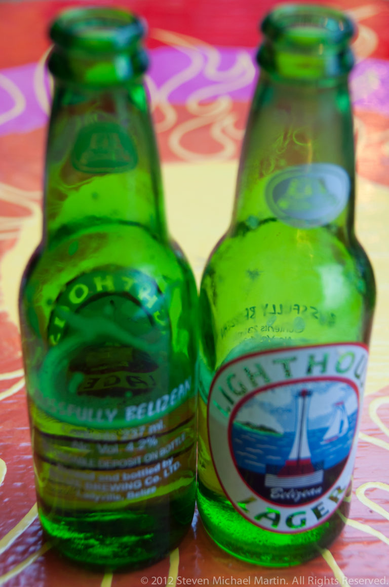 Two green Belikin beer bottles on a brightly colored patterned table in San Pedro.