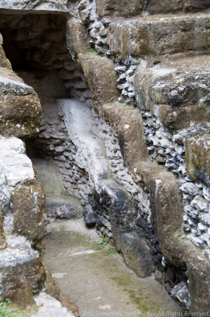 Narrow recessed channel between weathered stone masonry with layered construction visible along both sides.