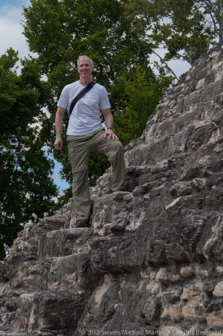 Visitor standing on steep weathered limestone steps at the Maya archaeological site of Yaxha.