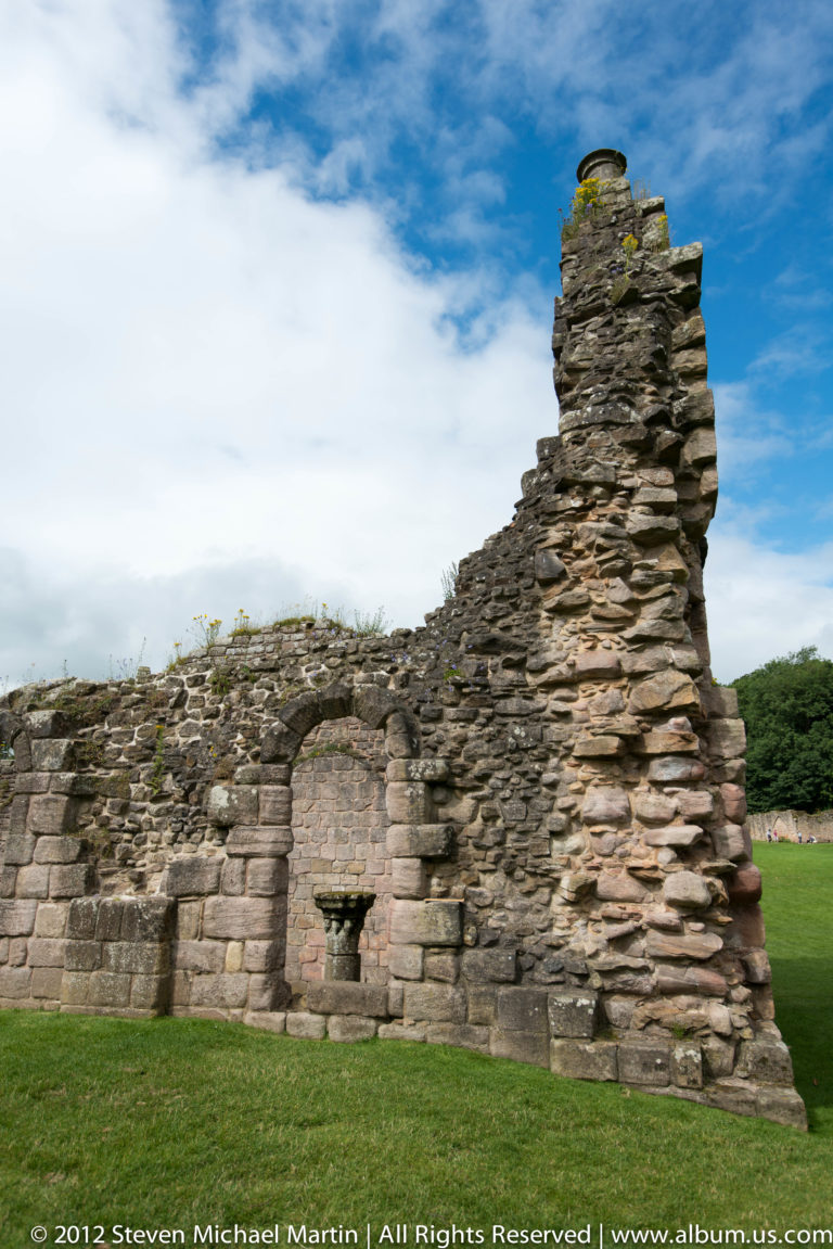 A broken stone wall contains a small low doorway near its base.
