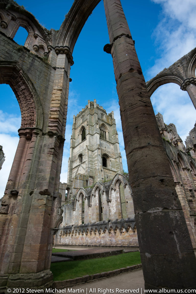 A steep upward view between church piers reaches a high stone arch.