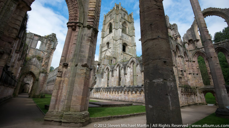 A pale church wall is framed by dark stone piers and arches.