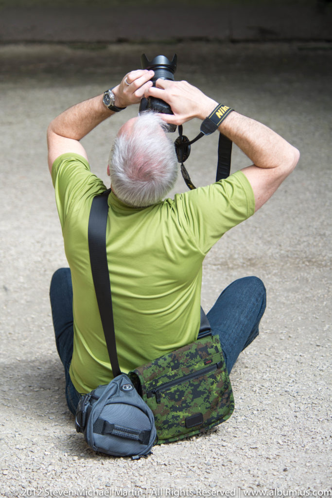 A visitor photographs the high stone walls inside the ruined abbey church.