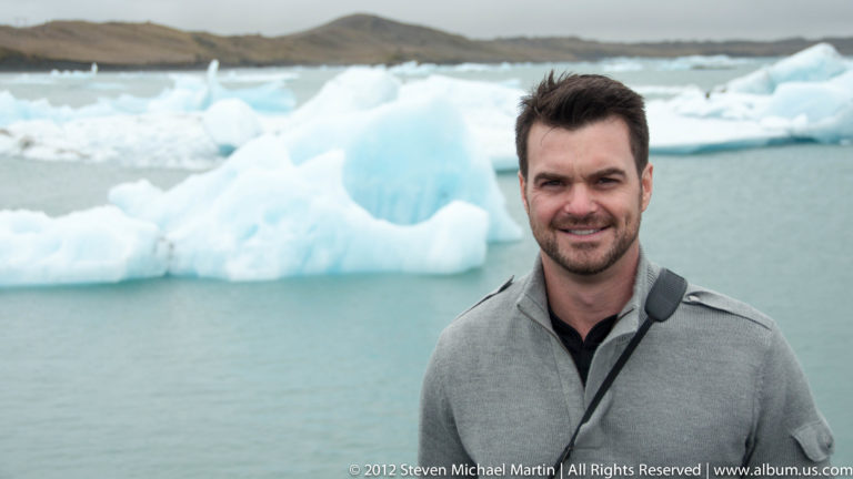A traveler stands before blue-white icebergs floating in Jökulsárlón glacier lagoon.