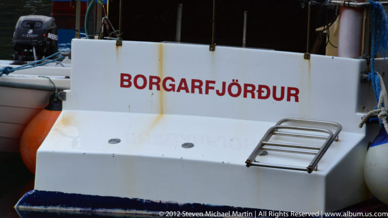 A white boat hull bears large red BORGARFJÖRÐUR lettering beside a metal boarding ladder.
