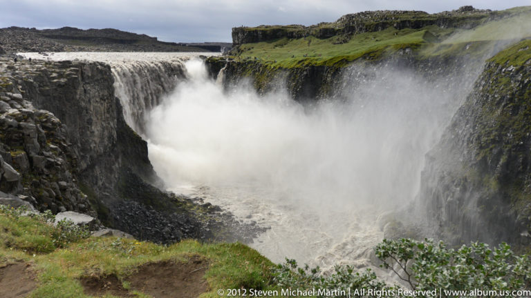 Goðafoss drops over a dark basalt rim into the misty gorge of the Skjálfandafljót River.