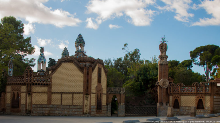 Decorative brick gate lodge with tiled roof, pinnacles, and patterned wall at the Güell Pavilions.