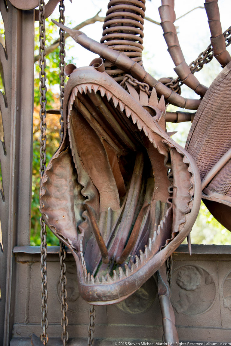 Close view of the open jaws and teeth of the wrought-iron dragon gate.