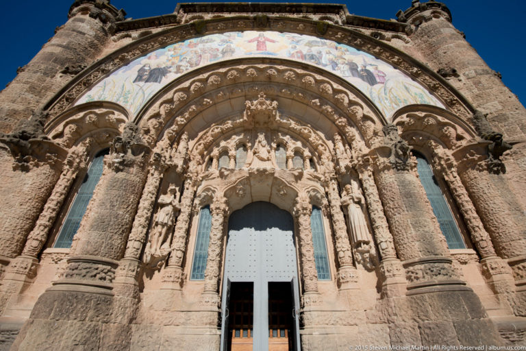 Low-angle view of a deeply carved church portal with mosaic frieze at Tibidabo.