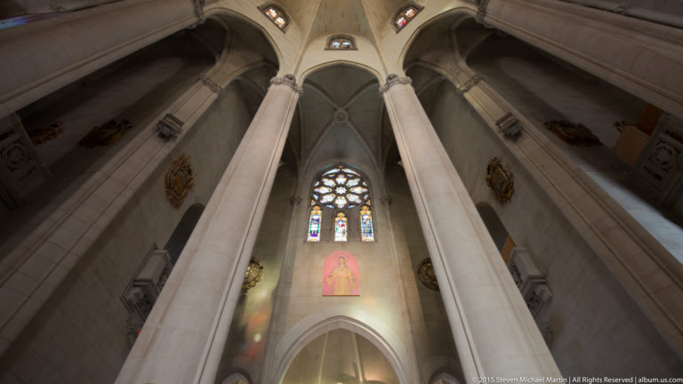 Tall stone piers rise toward pointed vaults and stained glass inside the Tibidabo church.