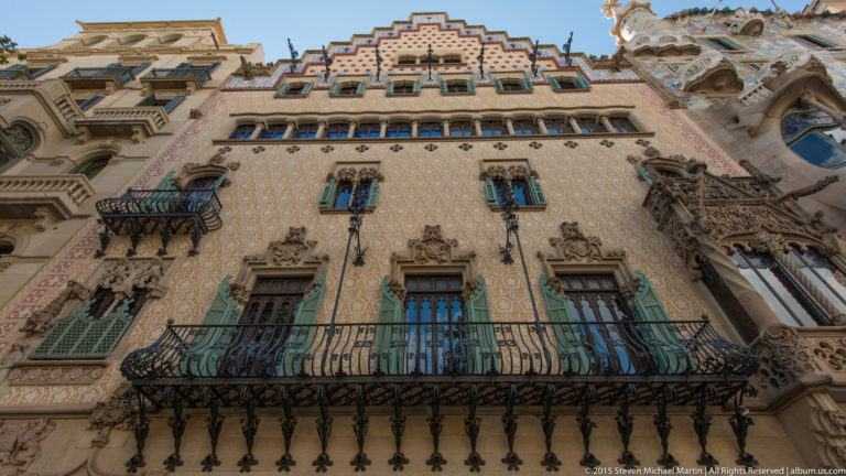 Casa Amatller façade with stepped gable, patterned walls, green shutters, and wrought-iron balconies.