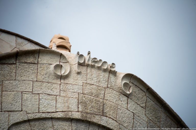 Curving rough-stone parapet with rounded openings along the roofline of Casa Milà.