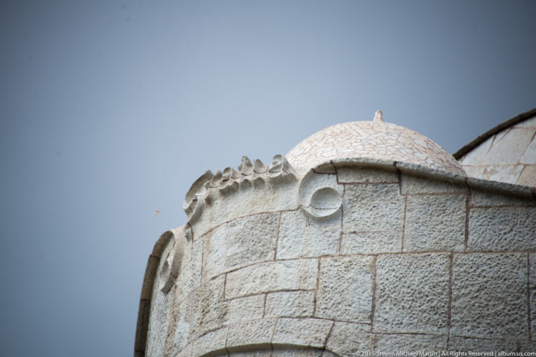Mosaic-covered rooftop form behind a curving stone parapet at Casa Milà.