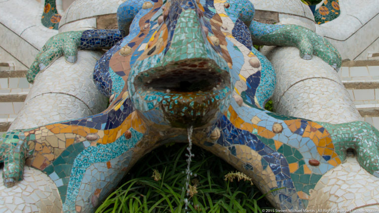 Colorful mosaic salamander fountain, El Drac, with water flowing from its mouth at Park Güell.