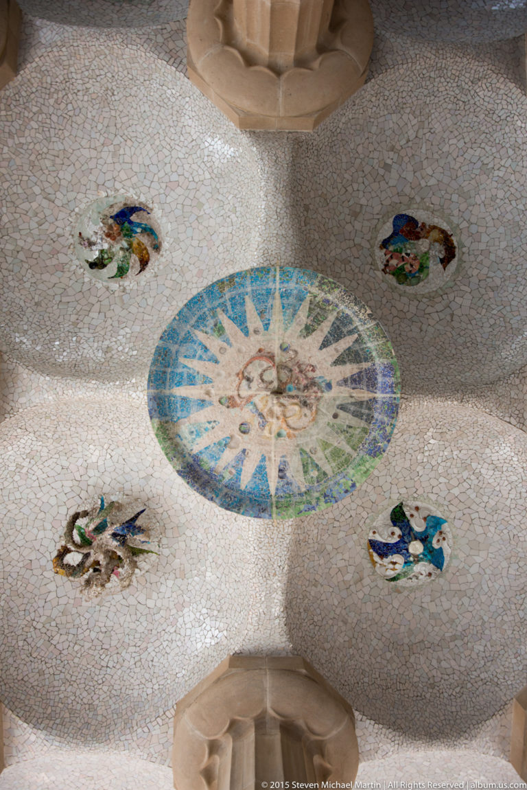Large blue-green mosaic ceiling medallion surrounded by four smaller round mosaics at Park Güell.
