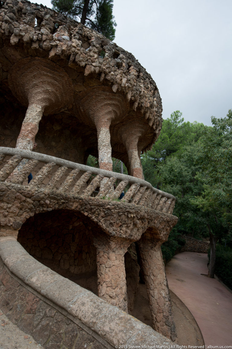 Curving rough-stone viaduct with open galleries and angled supports at Park Güell.