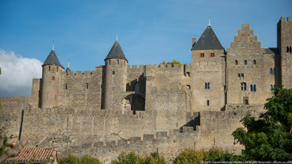 Close view of Carcassonne’s stone curtain walls, round roofed towers, square towers, and narrow openings.