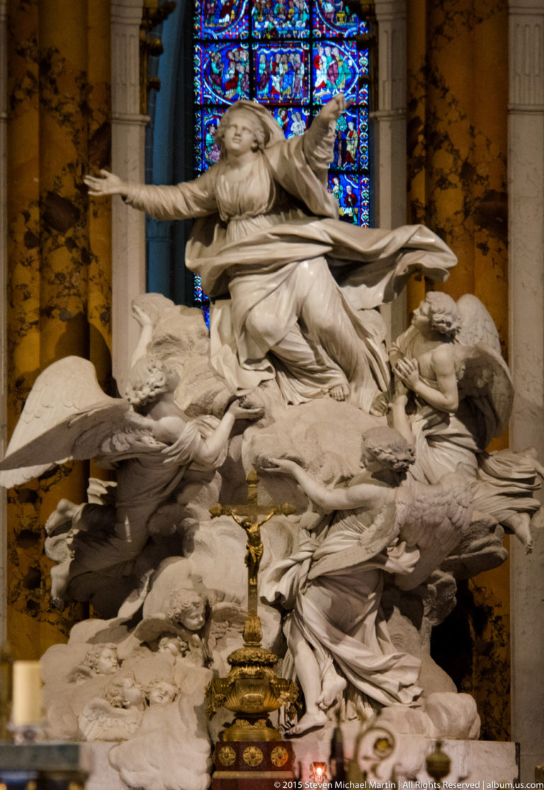 White marble Virgin Mary rises above clouds and angels in an elaborate sculptural group inside Chartres Cathedral.