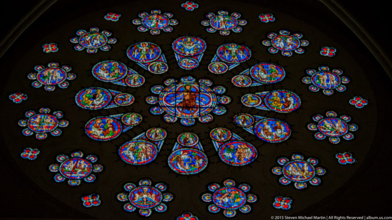 Large circular stained-glass rose with concentric blue and red figural medallions at Chartres Cathedral.