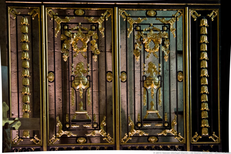 Dark paneled church furnishing decorated with symmetrical gilded garlands, urn motifs, and vertical ornaments in Chartres Cathedral.