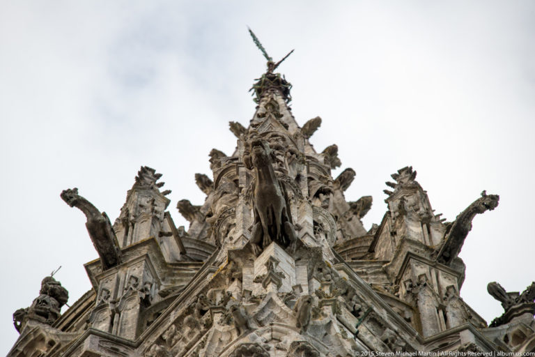 Ornate stone pinnacle with crockets, sculptural details, and projecting waterspouts on the roofline of Chartres Cathedral.
