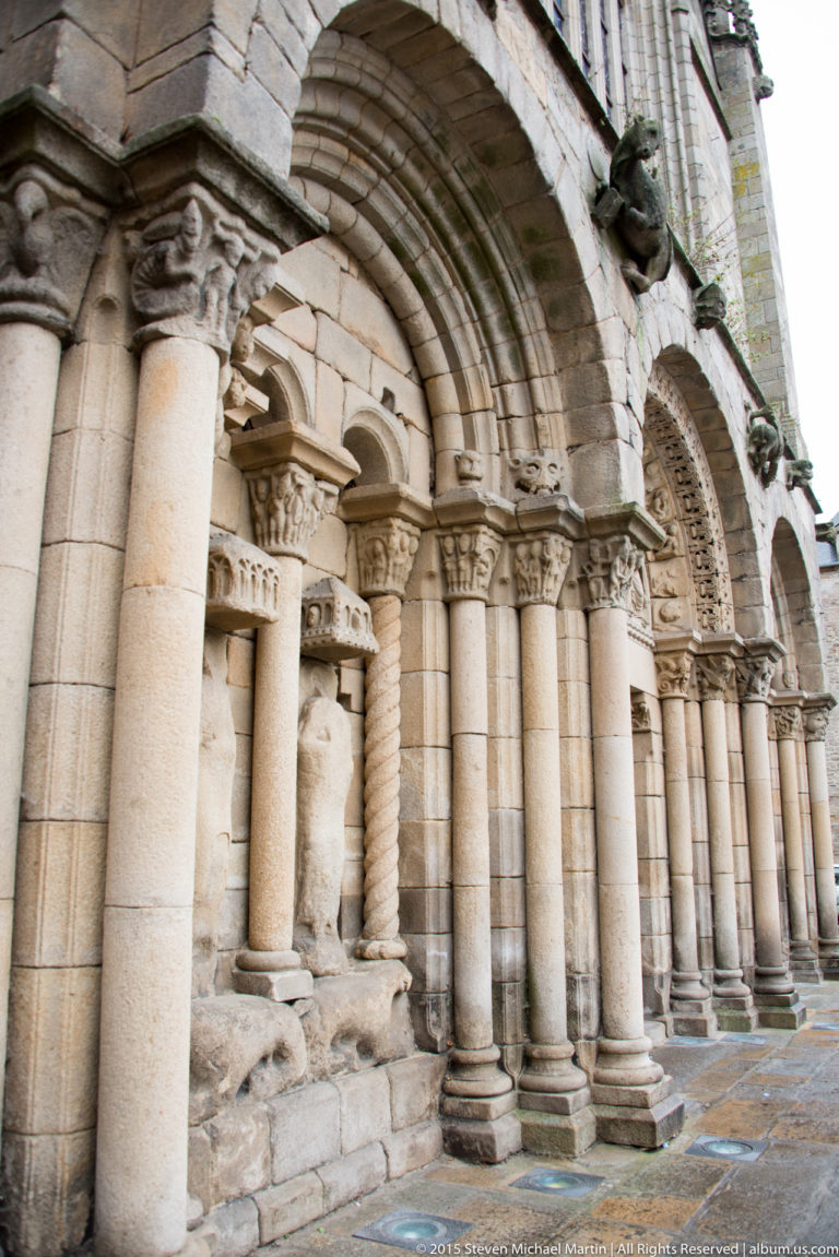Oblique close view of the Basilique Saint-Sauveur portal with rounded archivolts, columns, carved capitals, and sculpted figures.