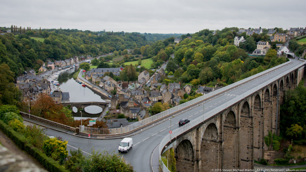 High view over the River Rance and lower Dinan with a long multi-arched stone viaduct crossing the valley.
