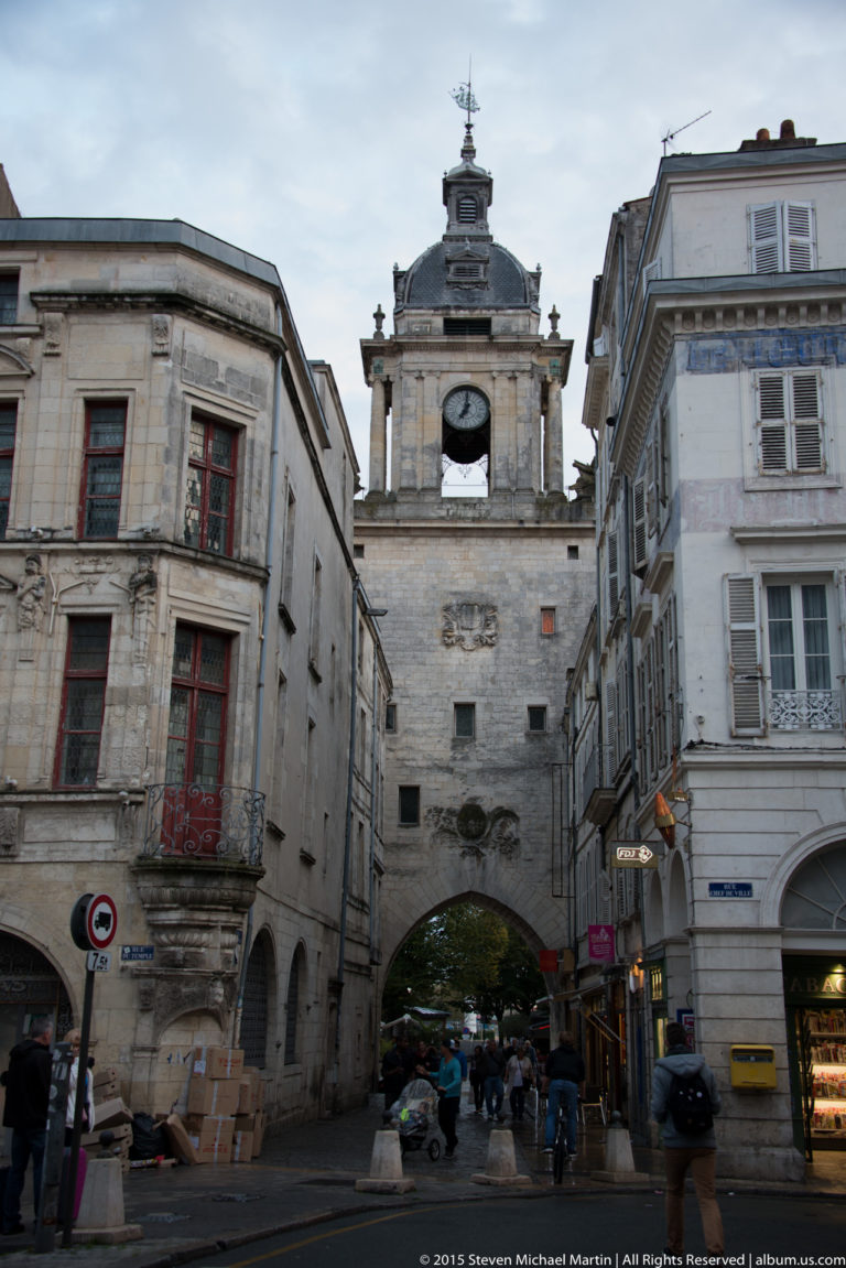 Grosse Horloge gateway with arched street passage and clock tower framed by historic buildings in central La Rochelle.