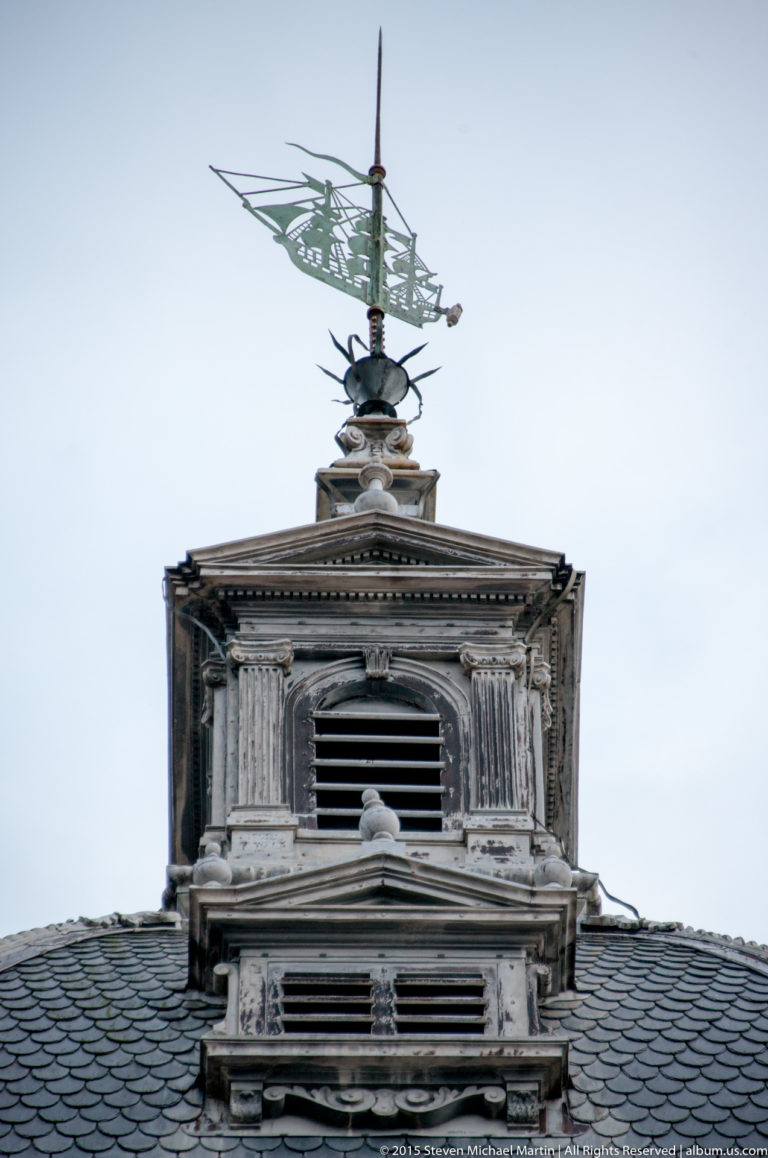 Decorative metal weather vane with a stylized sailing ship mounted above the roof of La Rochelle’s Grosse Horloge.
