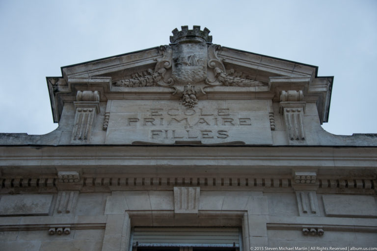 Ornate stone pediment with carved crest, scrollwork, and the inscription “FRITSCH MARTIN FILS” on a La Rochelle façade.