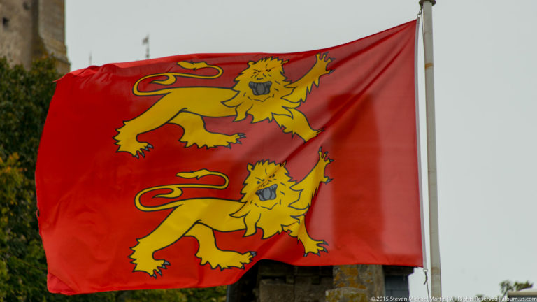 Red Normandy flag with two golden heraldic leopards flying from a pole.