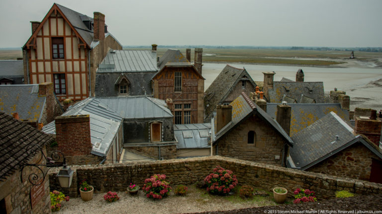 Slate rooftops, stone and half-timbered buildings, and a small garden within Mont Saint-Michel.