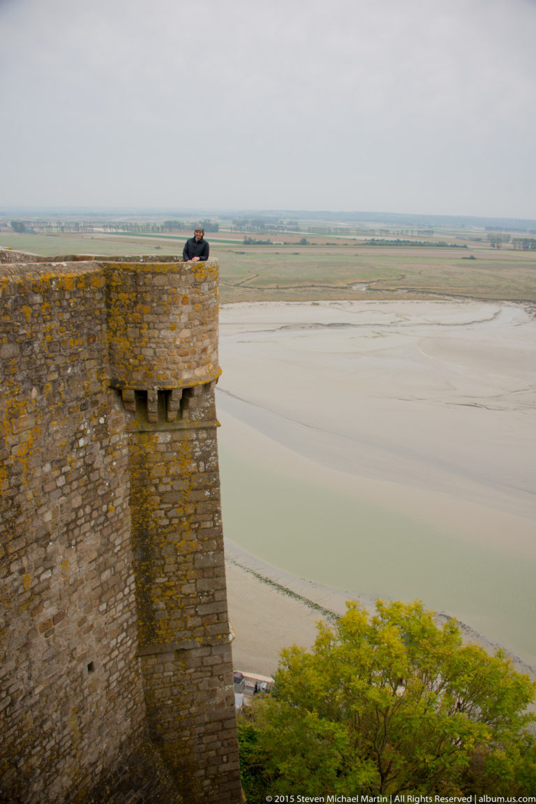 Projecting stone defensive tower with lichen overlooking the tidal flats of Mont Saint-Michel Bay.