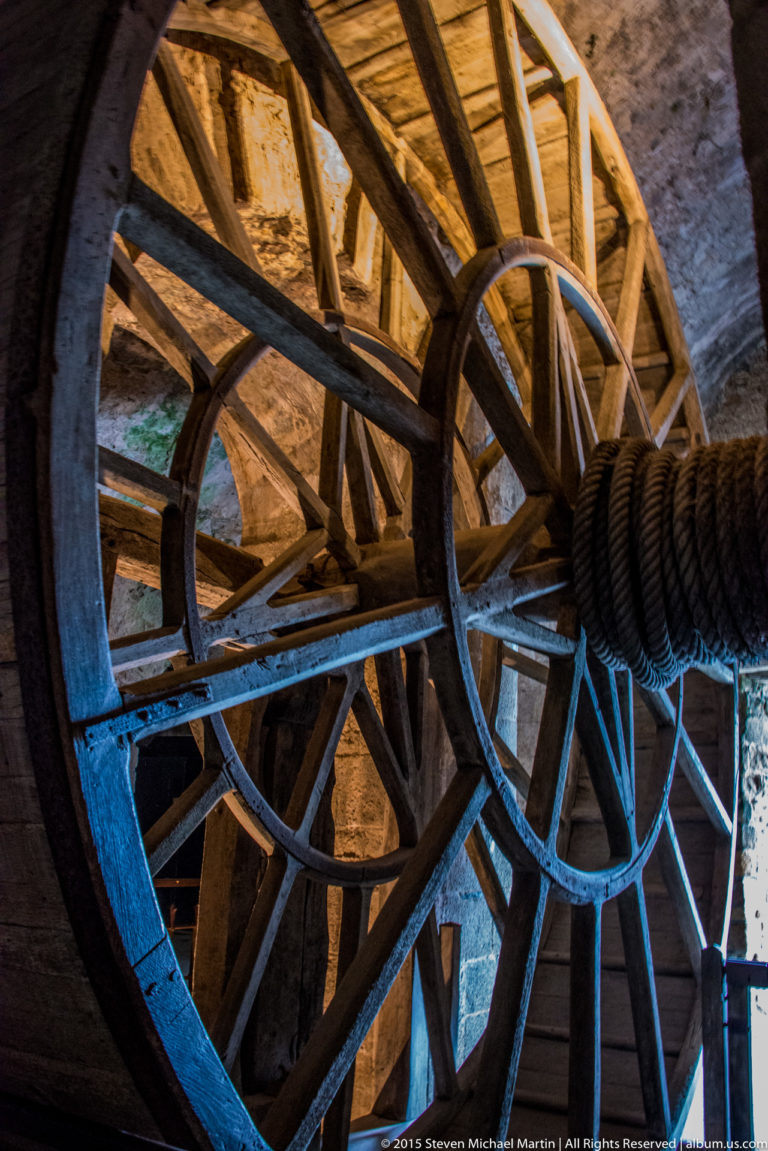 Large wooden treadwheel winch with heavy rope and timber spokes inside Mont Saint-Michel Abbey.