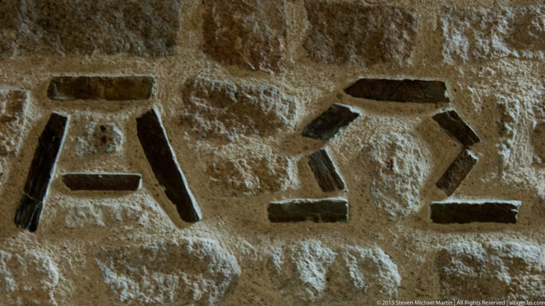 Several deeply cut angular symbols carved into a rough stone block.