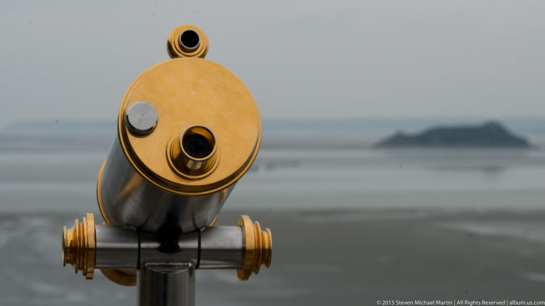 Brass-trimmed viewing telescope in sharp focus with the tidal bay blurred behind.