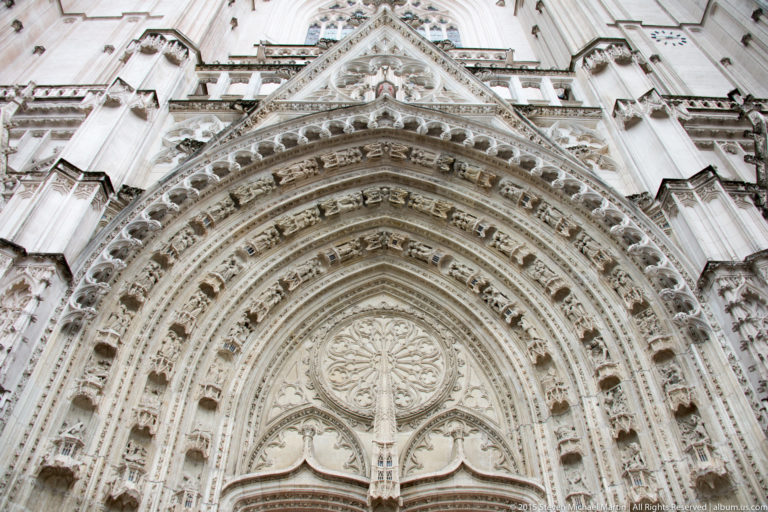 Close upward view of layered carved archivolts, pointed arch, tympanum, and traceried gable at Nantes Cathedral.